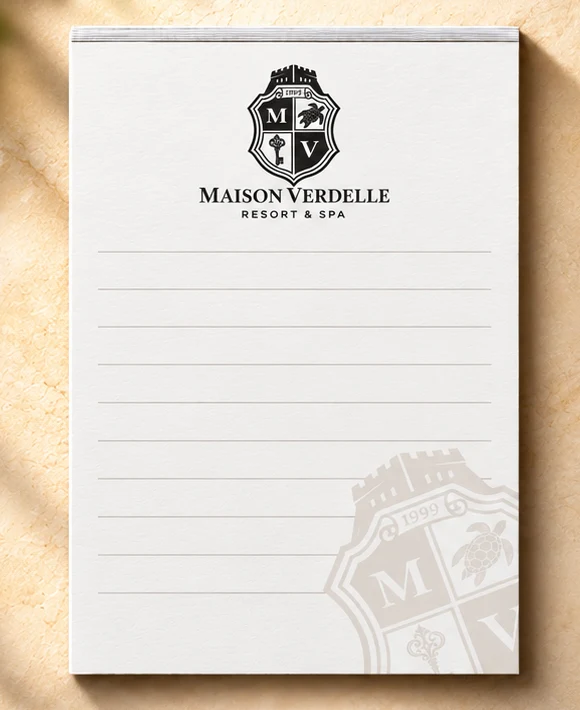 5 x 7 inch hotel notepad printed with a hotel logo, ruled lines and address, on a hotel desk
