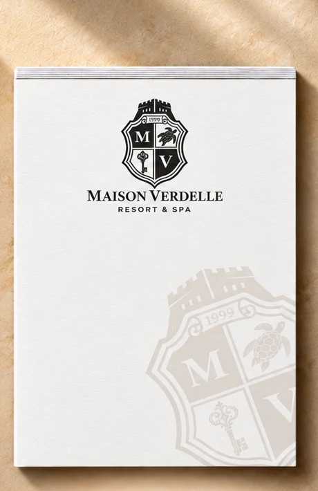 4.25 x 5.5 inch hotel room notepad printed with a hotel logo, next to a pen on a nightstand